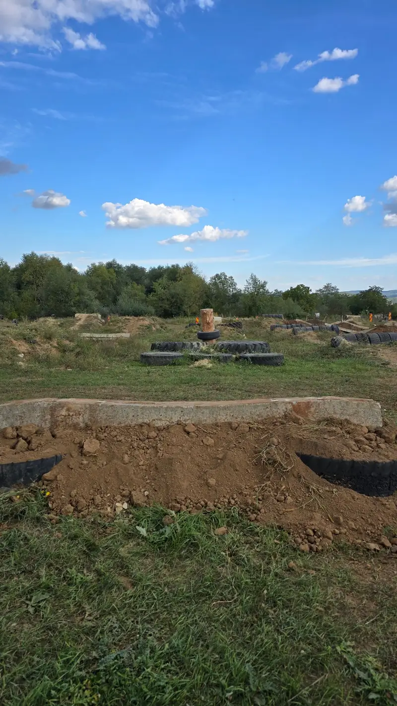 Grinda de beton peste o movila cu anvelope ingropate, iar in spate un butuc de lemn pe o insula de anvelope
